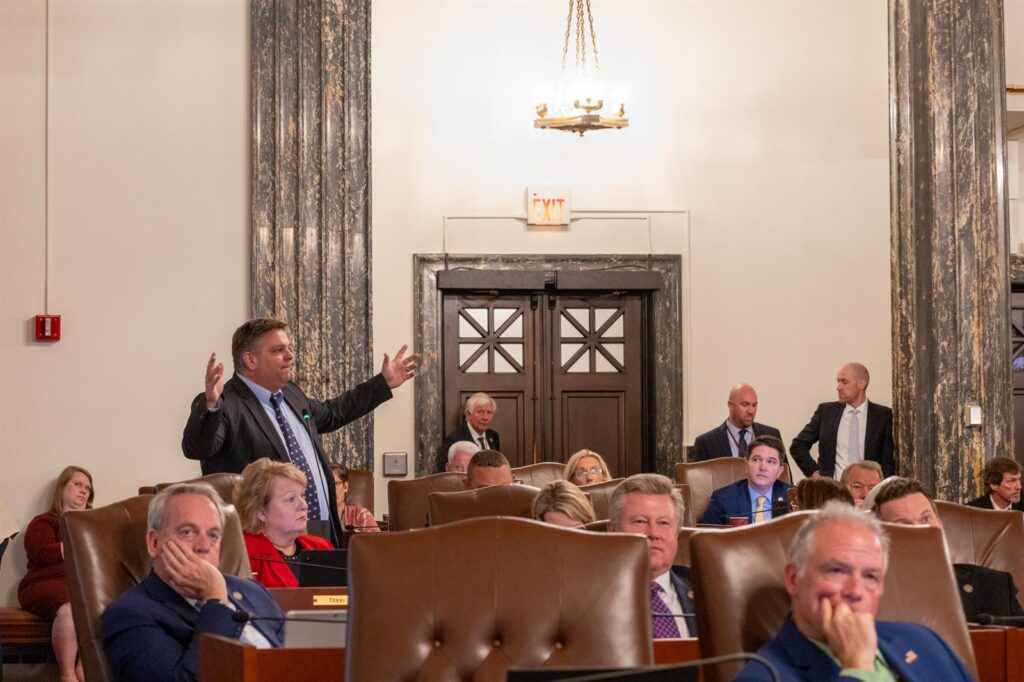 Sen. Chapin Rose raising and spreading his arms while speaking to a group of people.