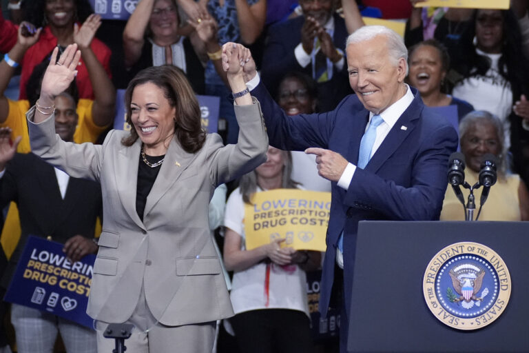 Vice president Harris and President Biden on stage holding hands at a rally