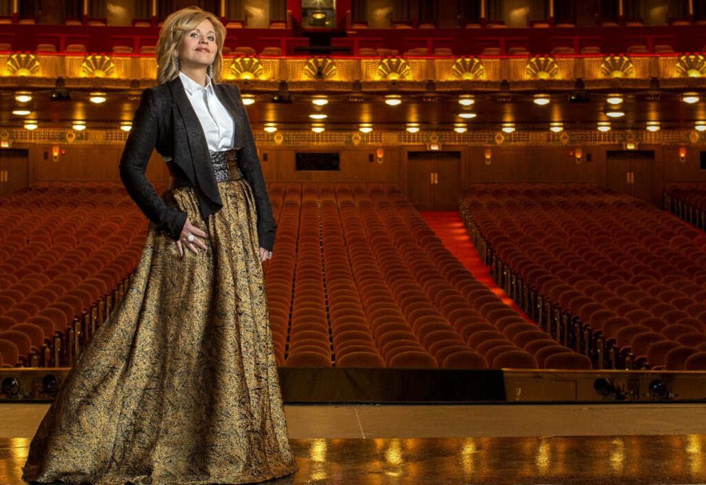 A woman stands on a stage in front of an empty theater.