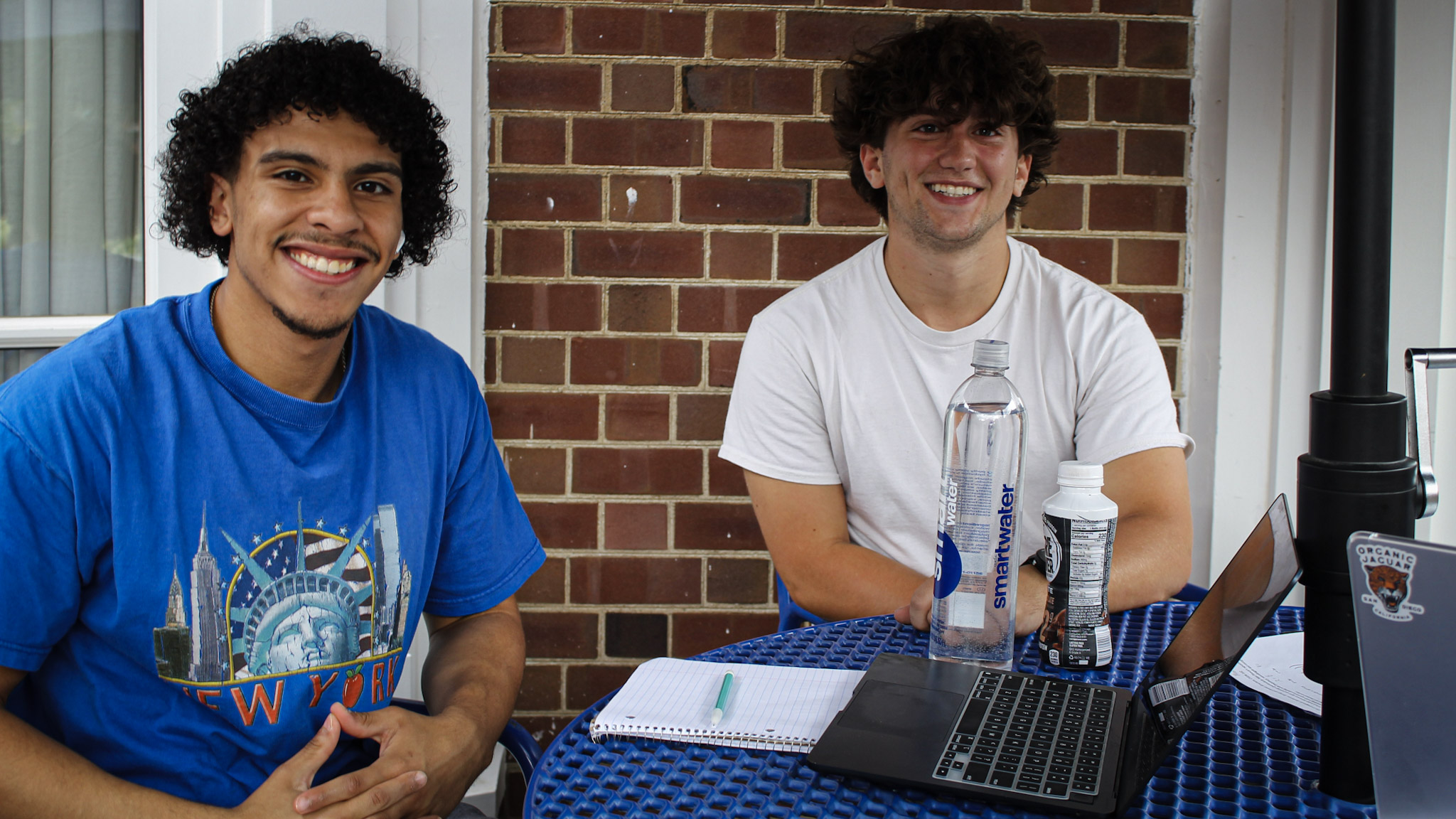 Two young men work on chemistry homework at an outdoor table by the Illini Union.