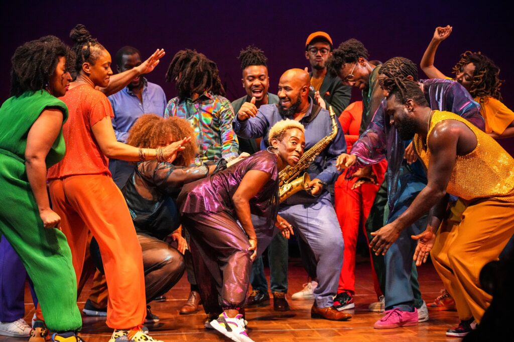 Performers in colorful clothing dance.