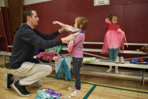 a man helps a girl put on a costume