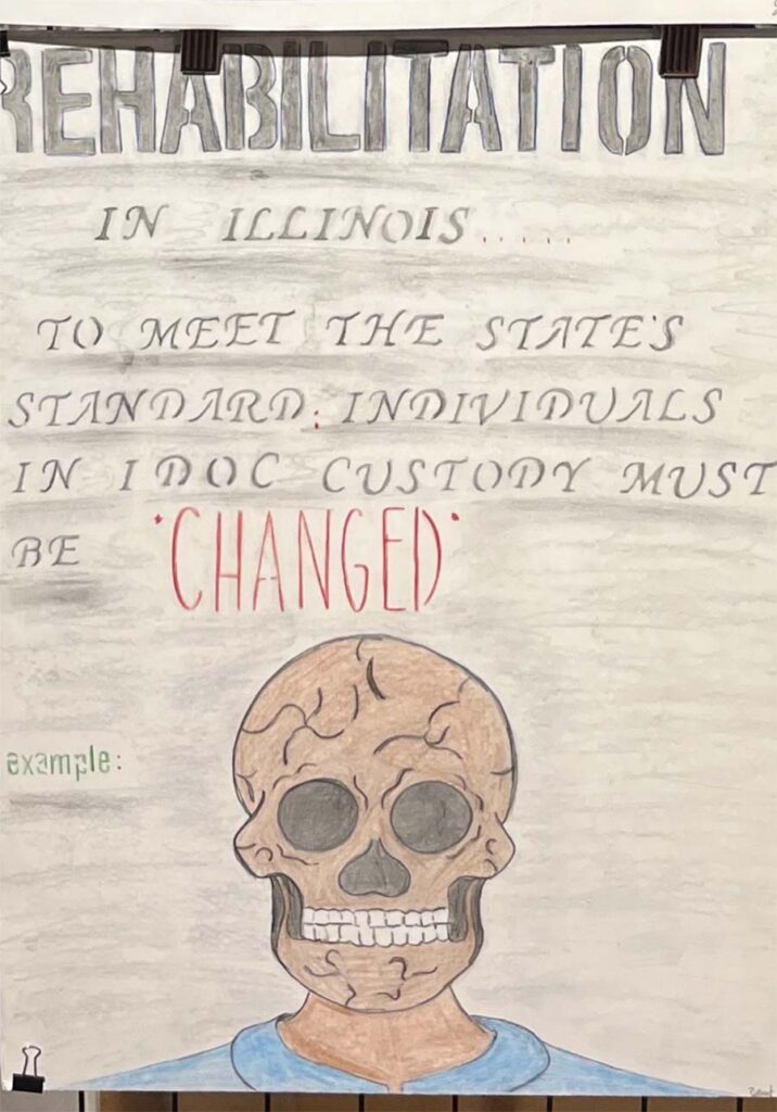 Text at the top of the drawing reads, "Rehabilitation in Illinois ... to meet the state's standard, individuals in IDOC custody must be *CHANGED* Example:" Below that text is a skull with fracture lines throughout on a neck and shoulders wearing a blue uniform.