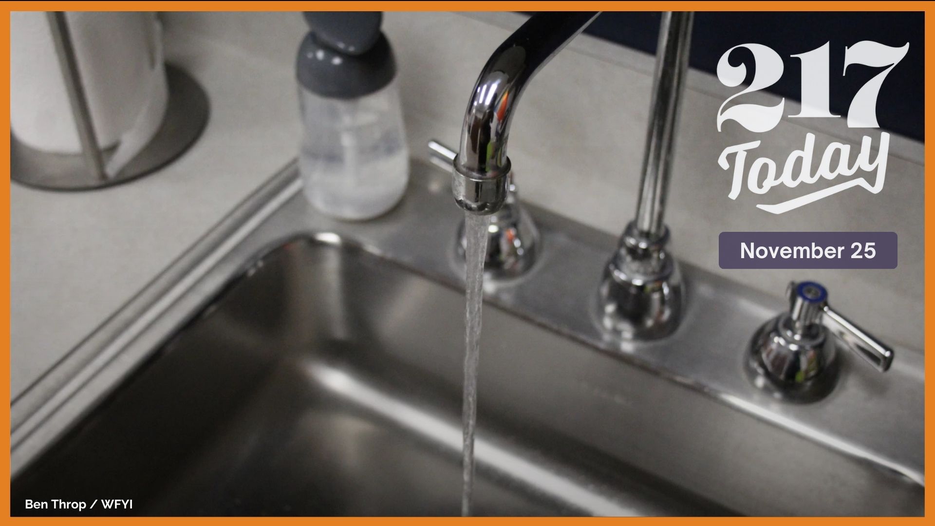 A faucet is turned on and water falls into a gray sink.