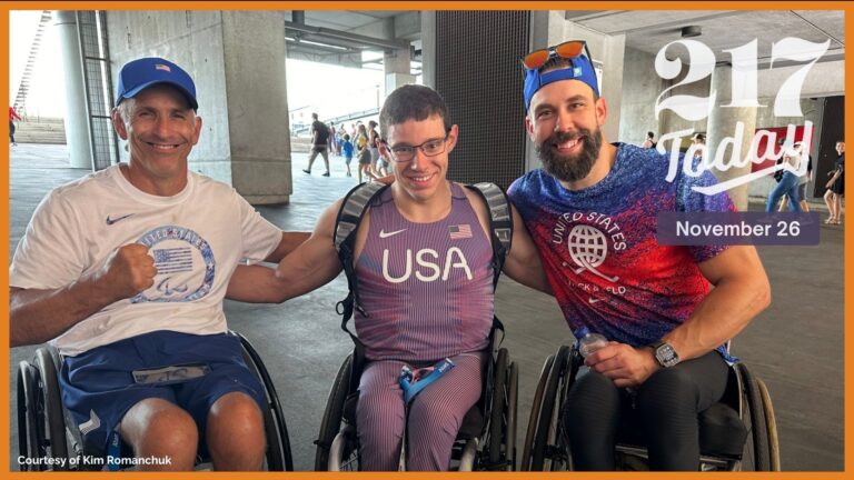 three men in wheelchairs pose for a photo with arms around each other