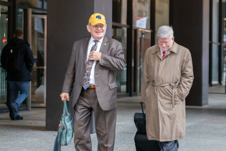 Two men stand outside a courthouse smiling.