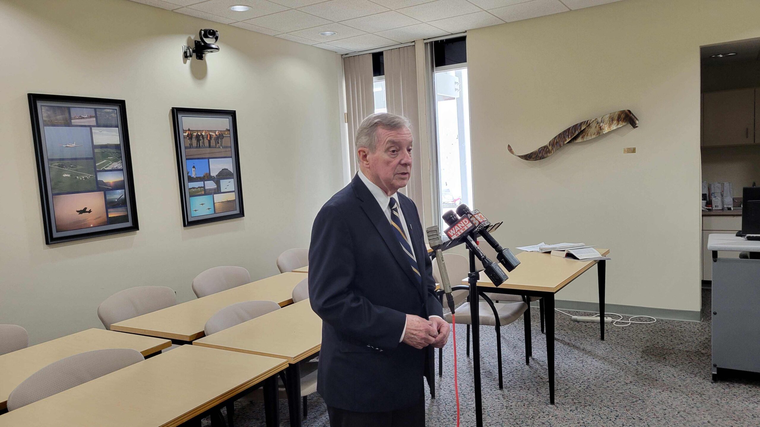 Senator Dick Durbin stands in front of a microphone indoors.