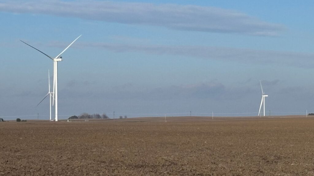 Wind turbines stand on a field.