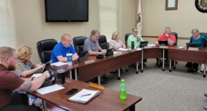 People sit in at tables in a room in a meeting.