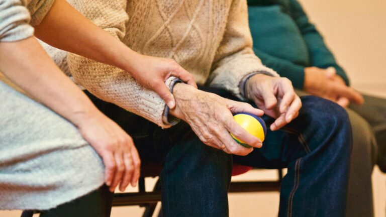 A person holds a stress ball while another person touches their wrist.