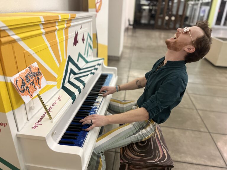 A man leans back while playing a piano.