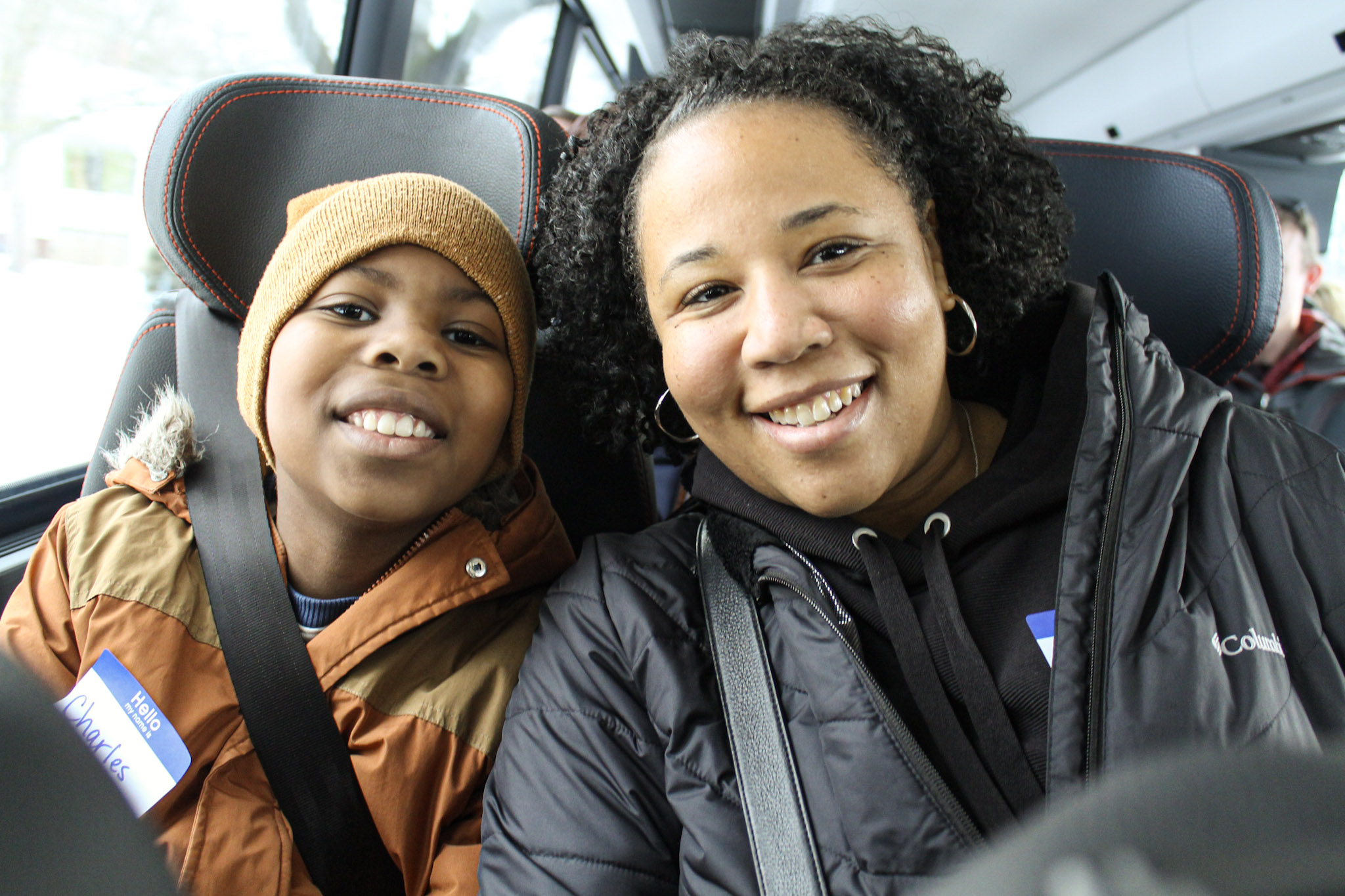 A son amd mother smile together in bus seats.