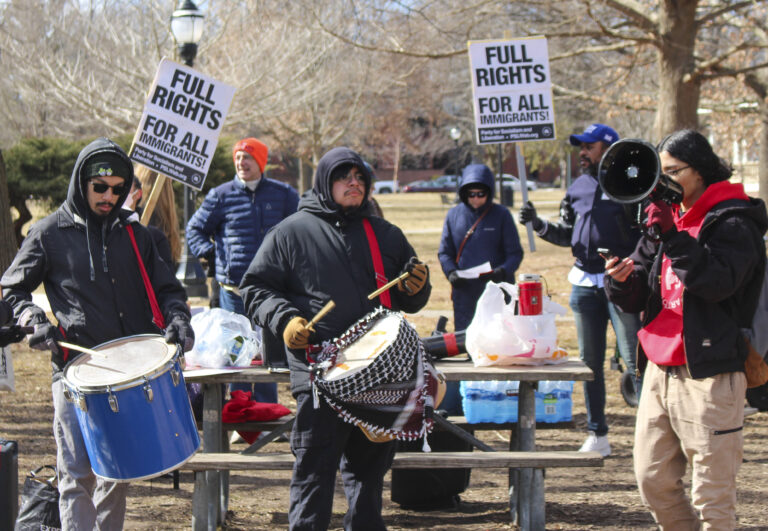 Protesters use drums and stand in front of signs that say "Full Rights for All Immigrants"