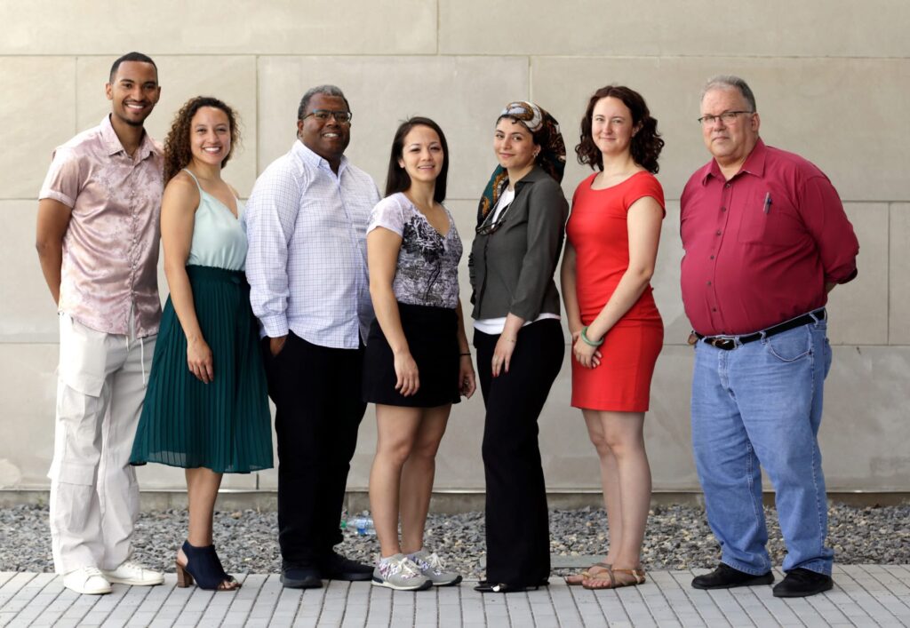 A group of people pose outside of a building