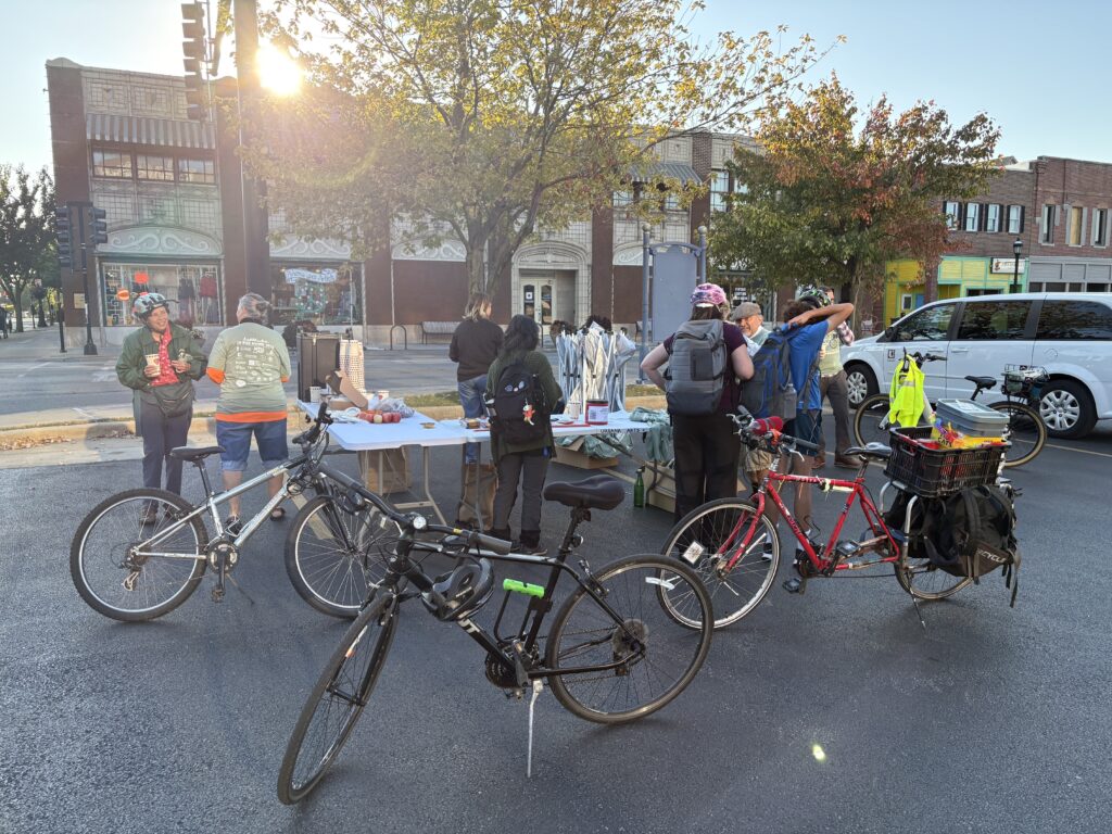 Bikes sit in front of a table where people check in to receive t shirts and free pastries.