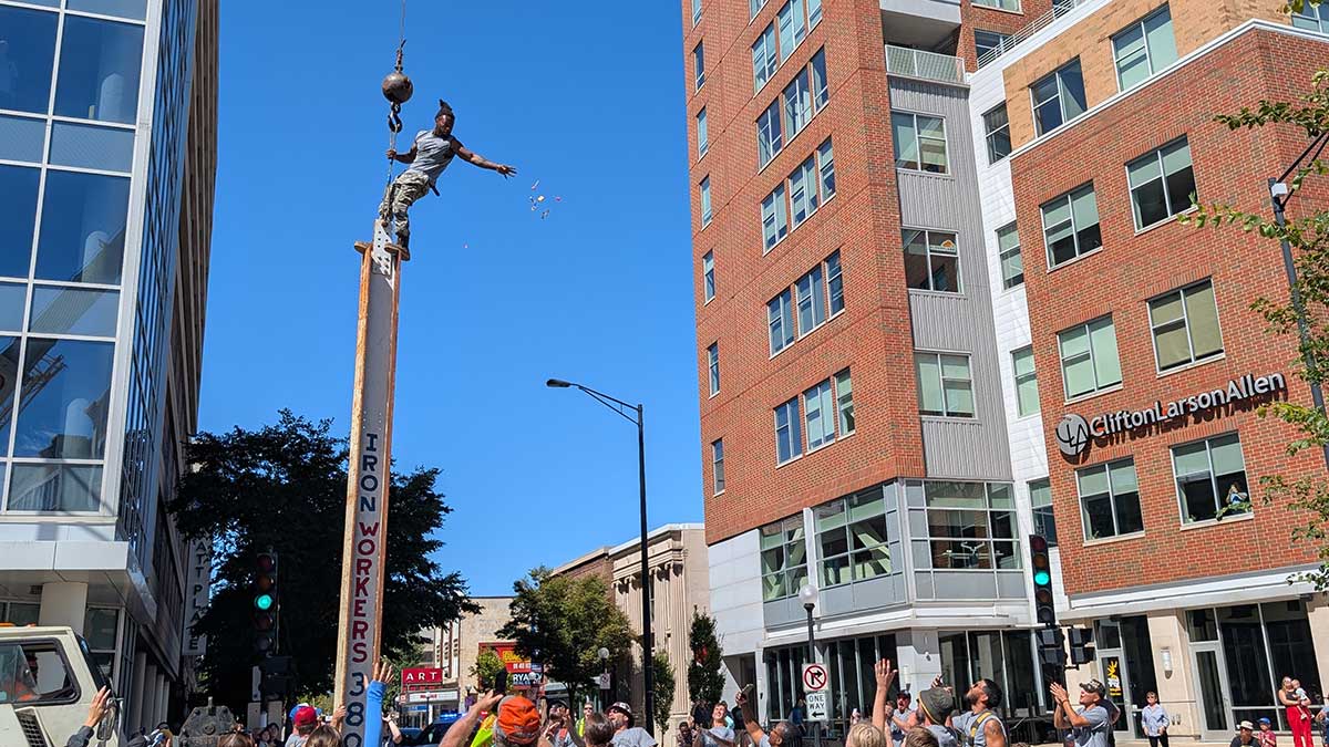 a man on an iron beam throws candy to a crowd