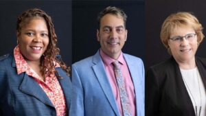 Three headshots of (from left) a Black woman, a white man and a white woman. All are wearing suits and smiling.