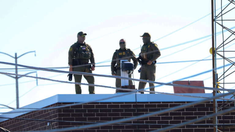 masked men standing on building