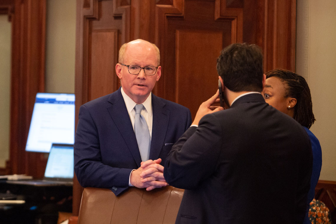 man speaks behind chair