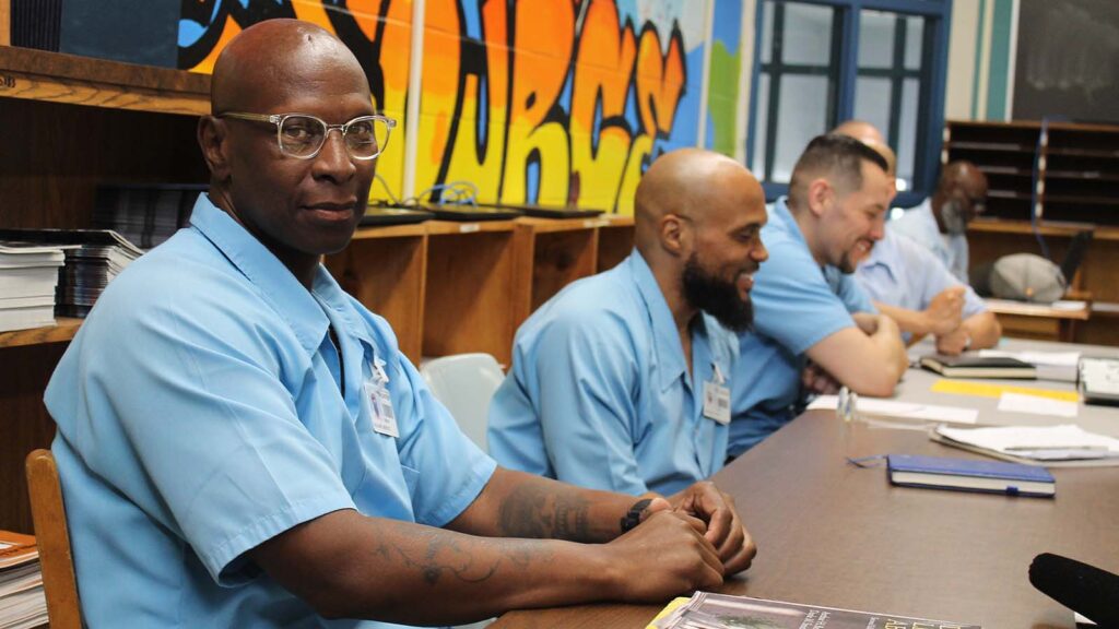 Maurice Williams gives the camera a model stare while three men next to him laugh.