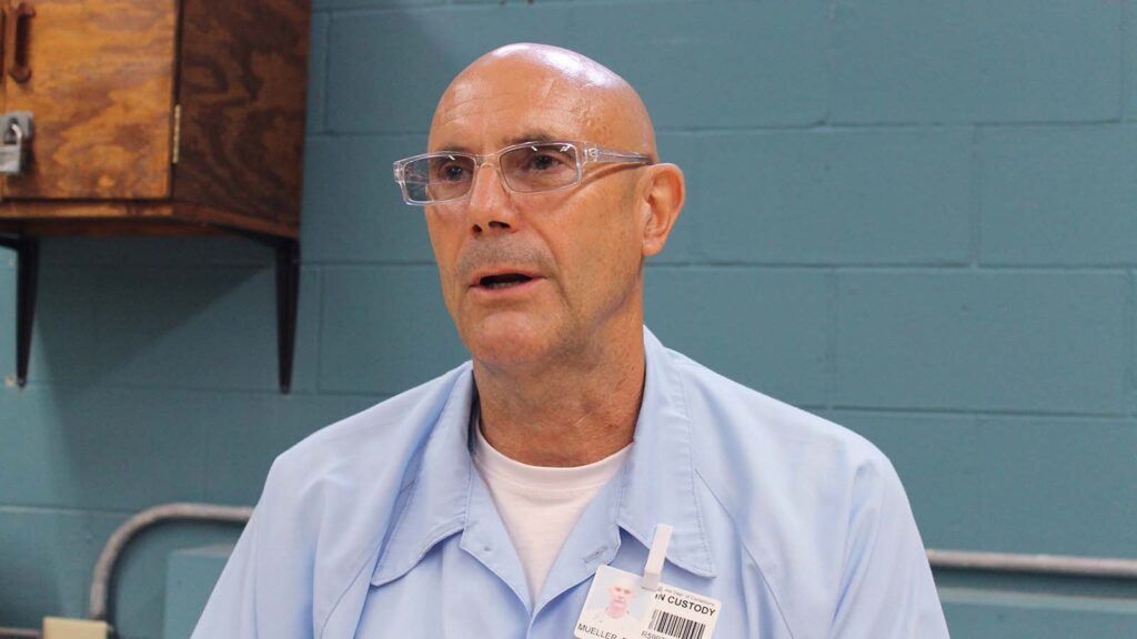 A man with glasses looks to the side.