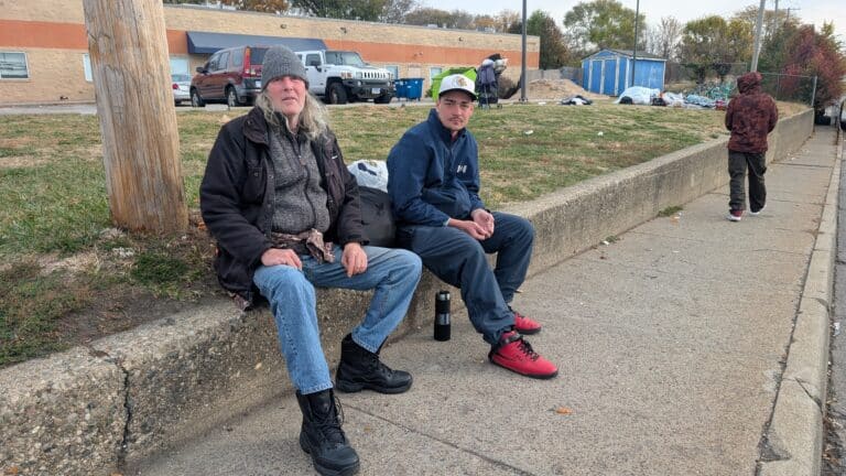 Two men sit outside