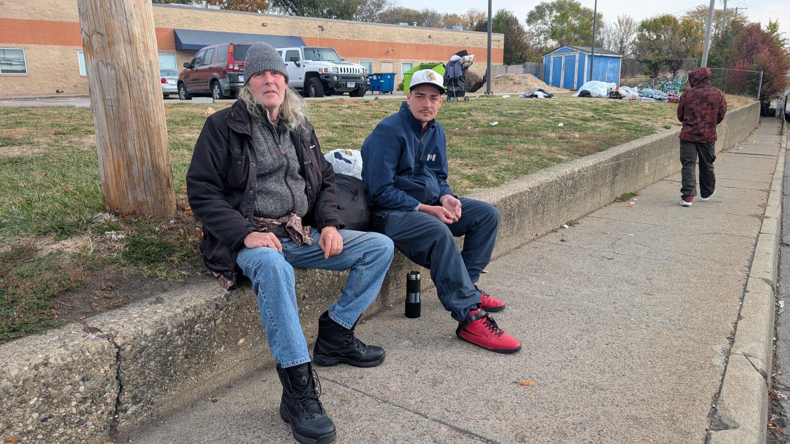Two men sit outside