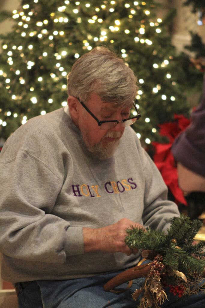 A man uses plant materials to create a Christmas decoration.