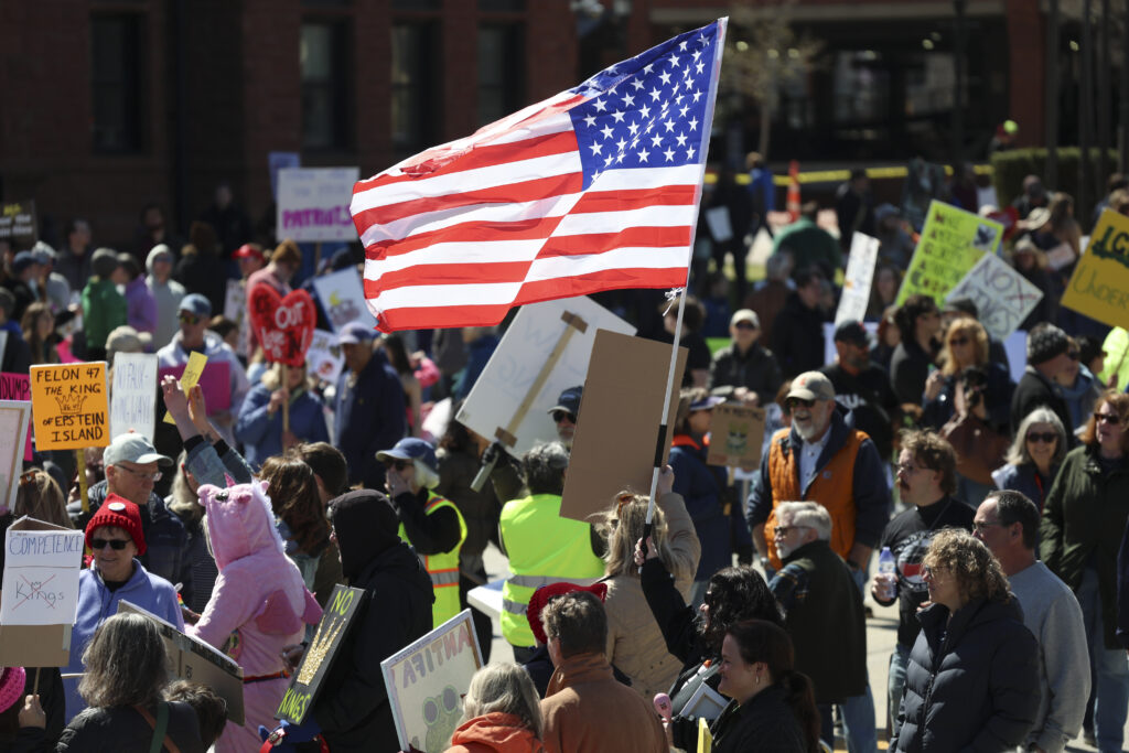 A crowd of protesters and an American flag