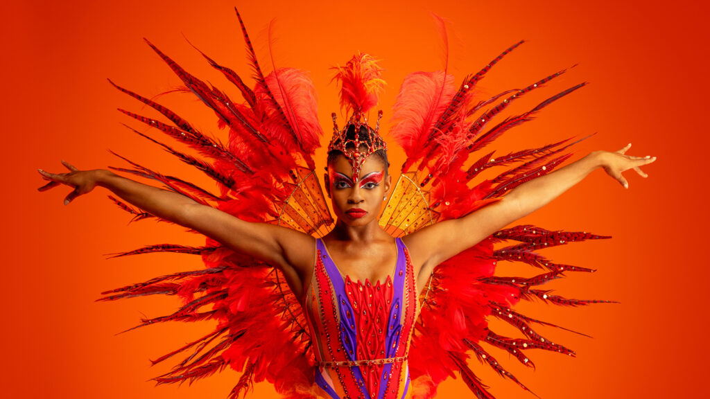 A woman in a colorful costume poses.
