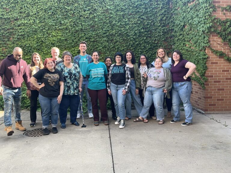 A group of people pose in while all wearing jeans.
