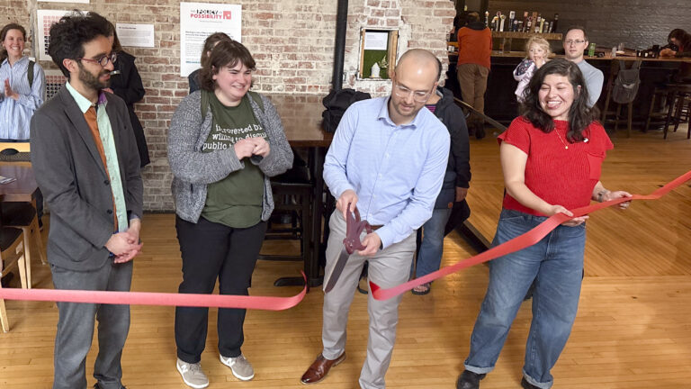 a person cuts a ribbon while three other people look on