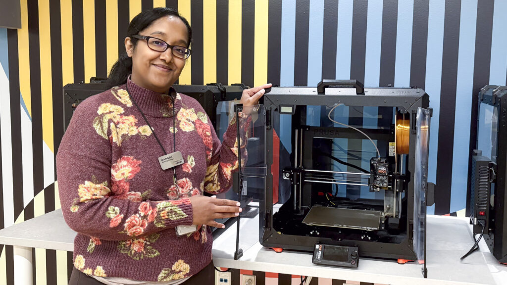 a person stands next to a 3D printer