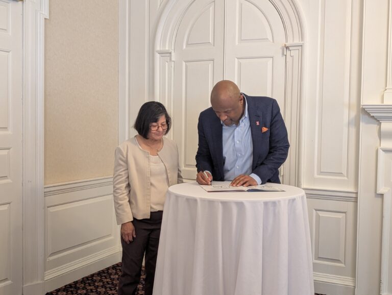 University of Illinois Urbana-Champaign Chancellor Charles Isbell Jr. (right) signs an agreement as Director of the Institute for Sustainability, Energy and the Environment Madhu Khanna (left) looks on.