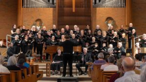 A group of people sing together on a stage in a church.