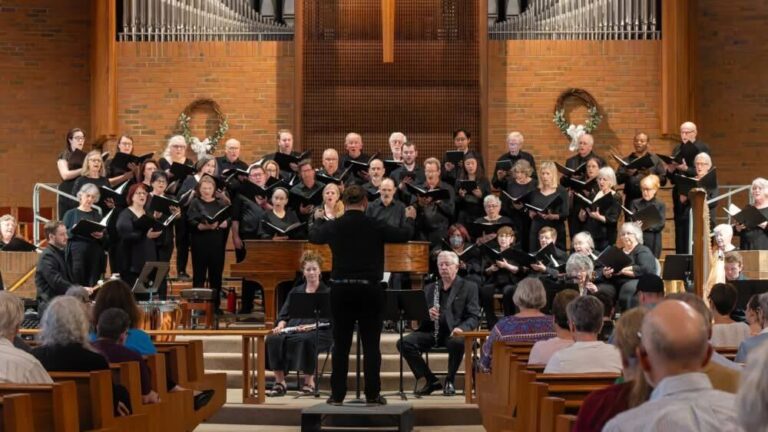 A group of people sing together on a stage in a church.