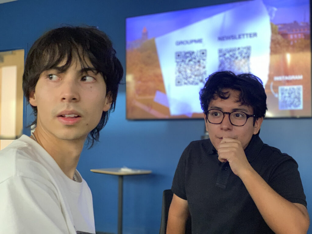 two people look to the side, a TV screen is behind them