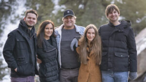 five people stand a pose for a photo outside