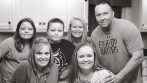 A black and white photo of a family standing in a kitchen.