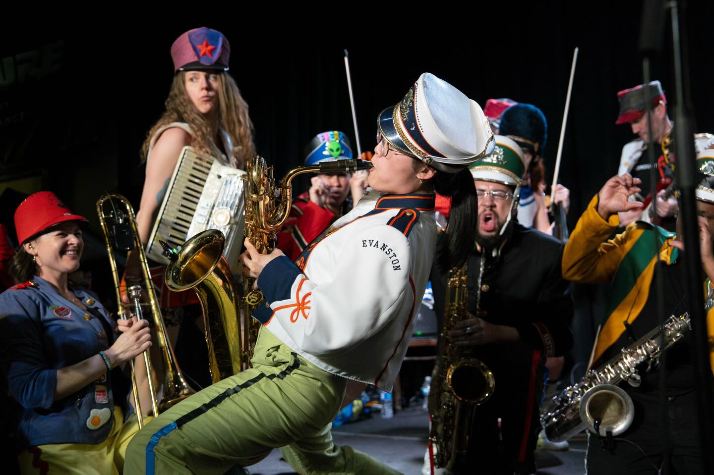 Performers play instruments in marching band inspired outfits.