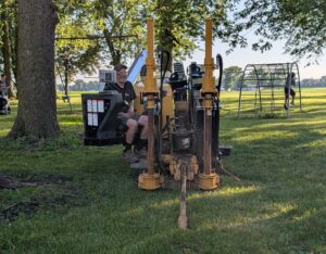 A man operates a directional boring machine that's digging into the ground.