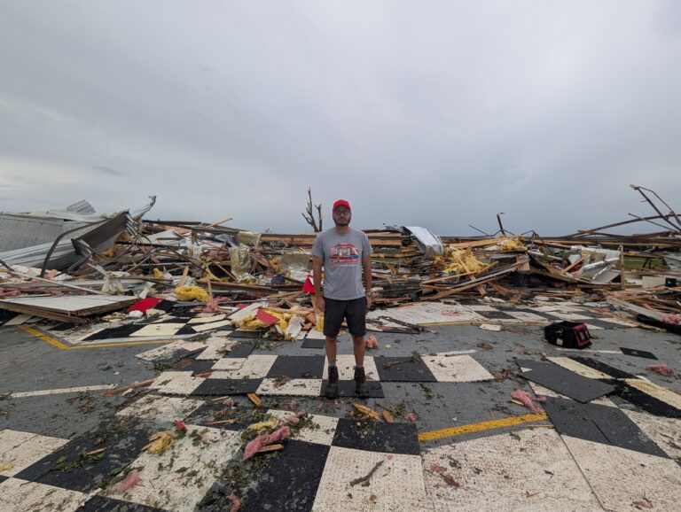 A man stands in front of a pile of rubble.