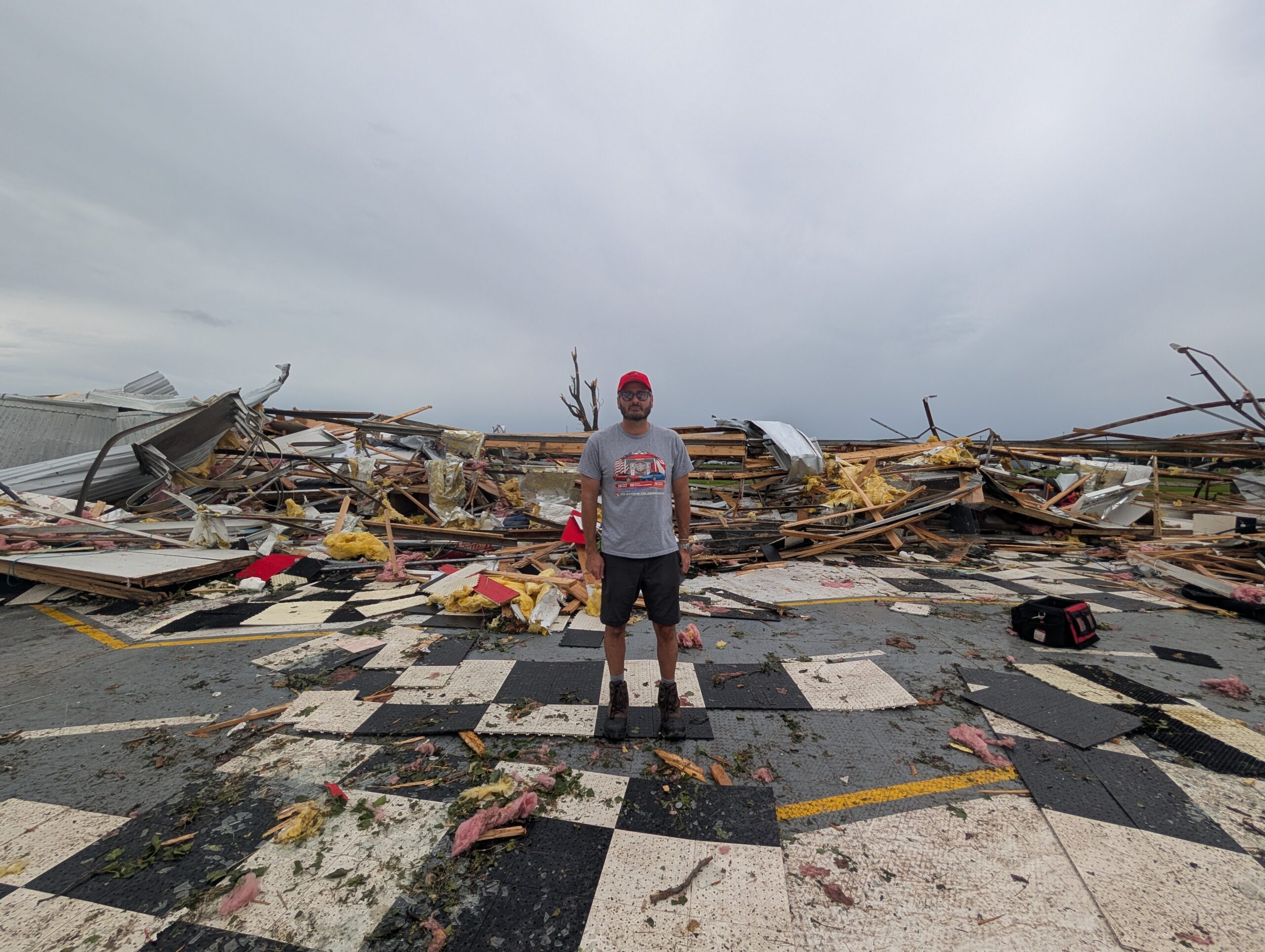 A man stands in front of a pile of rubble.