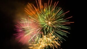 Multi-colored fireworks burst against a black sky.