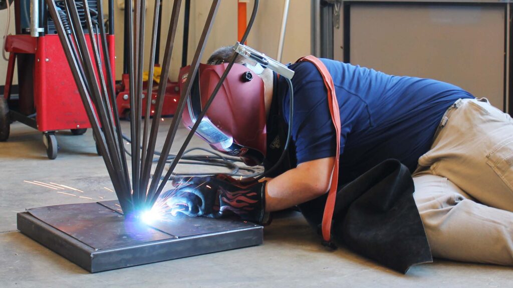 Malakai Hyman fuses two pieces of metal together for a side project in Unit 4's 2026 summer welding program.
