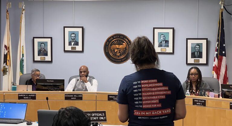 Public speaker at Urbana City Council with housing advocacy shirt