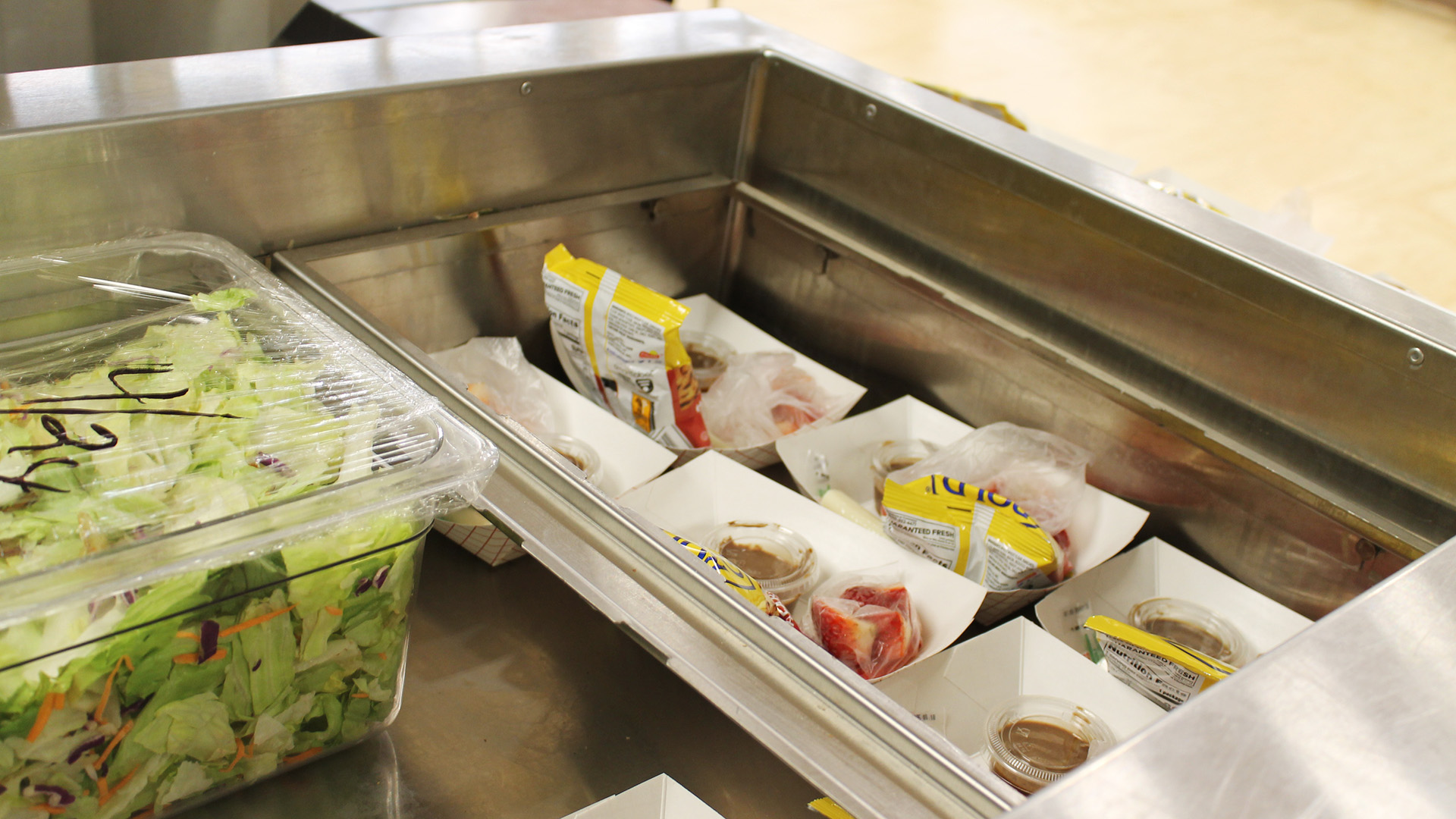 This is a generic school lunch photo from an elementary school in Urbana, IL. It shows six boxes with pretzels and chocolate dip, as well as a tub of salad.