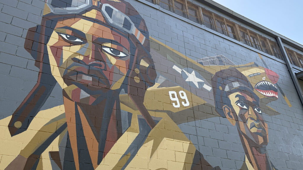 a mural shows two Tuskegee Airmen and a plan flying behind them