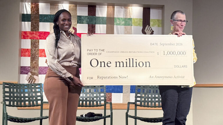 two people hold a check for $1 million from an anonymous donor
